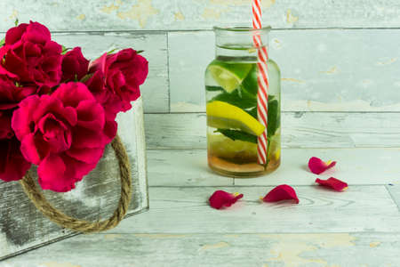 Red roses with a bio lemonade on a wooden tableの写真素材
