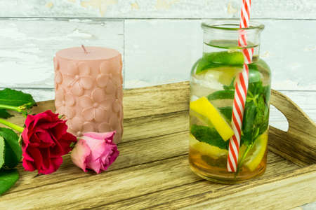 Red roses with a bio lemonade on a wooden trayの写真素材