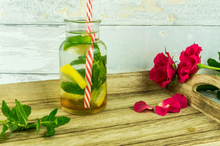 Red roses with a bio lemonade on a wooden trayの写真素材