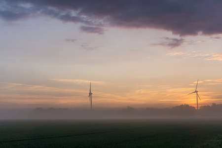 wind wheels at sunrise and fog with dark clouds