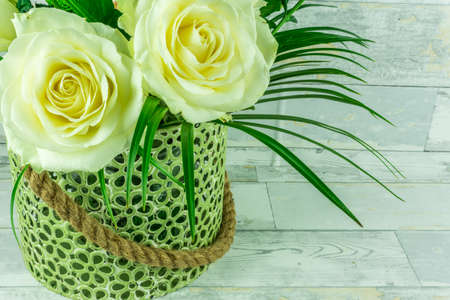 White roses in a green vase on a rustic wooden tableの写真素材