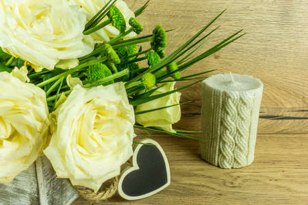 White roses with green leaves and a heart on a rustic wooden tableの写真素材