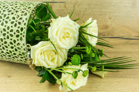 White roses with green leaves on a rustic wooden tableの写真素材
