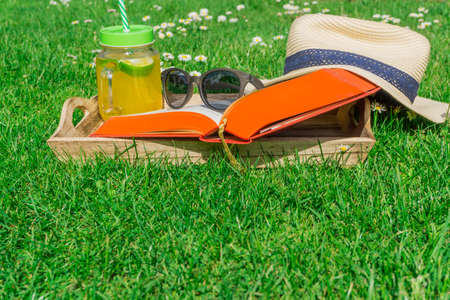 Straw hat with a book and sunglasses on a green lawnの写真素材