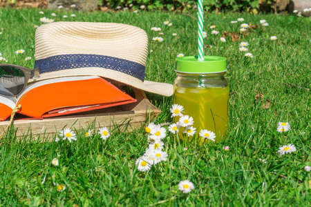Straw hat with a book and sunglasses on a green lawnの写真素材