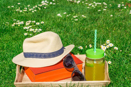 Straw hat with a book and sunglasses on a green lawnの写真素材
