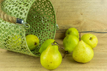 Green pears in a basket on a rustic wooden tableの写真素材