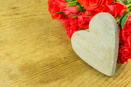 Red roses on an old board with a heart as a backgroundの写真素材