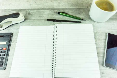 Notebook with coffee, pen and cell phone on a deskの写真素材