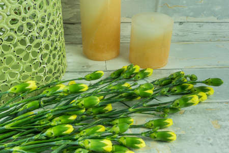 Yellow carnations with candles on a rustic undergroundの写真素材