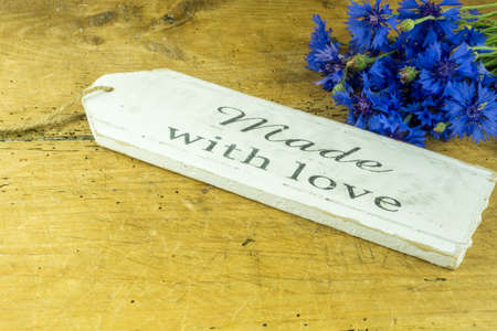 Rustic wooden board with cornflowers and a sign - made with love