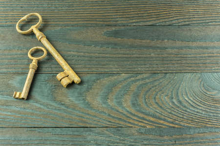 A rustic wooden board with two old keys as a backgroundの写真素材