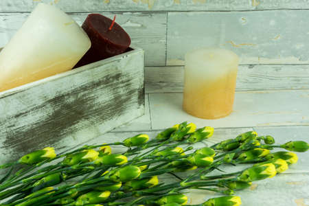 Rustic background of wood with candles and yellow carnationsの写真素材