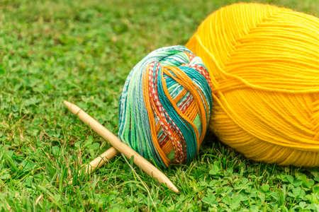 Knitting wool for summer on green lawn in sunshine with needlesの写真素材