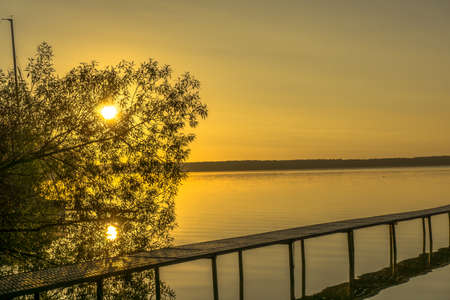 Sunrise on a lake with moorings for boatsの写真素材