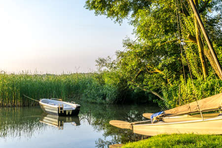 Boats on a lake at sunrise with reed in the backgroundの写真素材