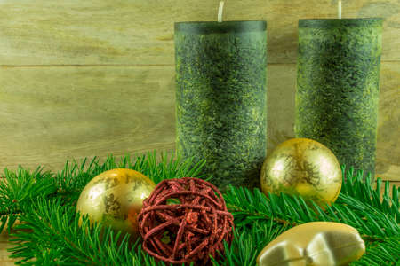 Christmas decoration - green candles with christmas balls and fir branch on a rustic boardの写真素材