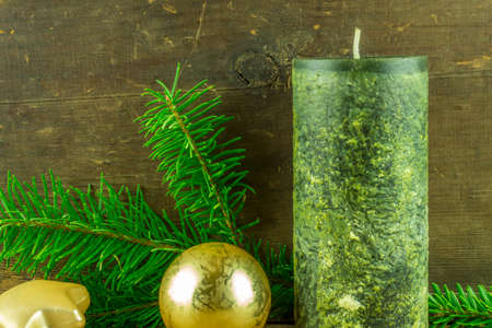 Christmas decoration - green candles with christmas balls and fir branch on a rustic boardの写真素材