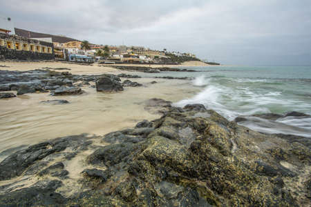 Beach with stones and waves and in the background some housesの写真素材
