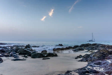 Beach with blue sky, blue water and a sailboatの写真素材