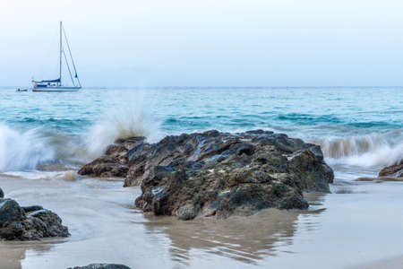 Beach with blue sky, blue water and a sailboatの写真素材