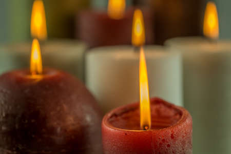 Many burning candles in different colors with a blurry backgroundの写真素材