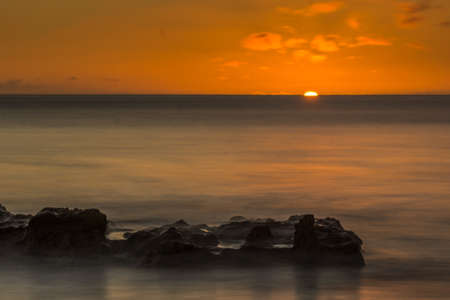 Beach with small waves at the Atlantic Ocean at sunset and lava stonesの写真素材