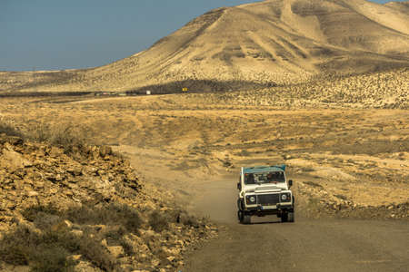 A car drives through a sand desert on Fuerteventuraの写真素材