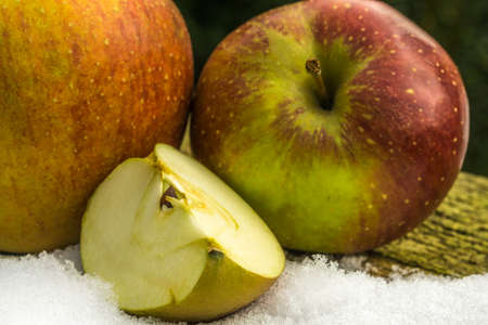 red apples in the snow on a rustic wooden boardの写真素材