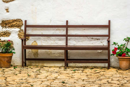a wooden bench with flowers in an old yardの写真素材
