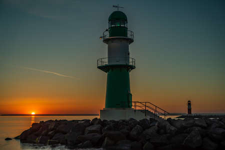 The entrance to a harbor with lighthouse at beautiful sunsetの写真素材