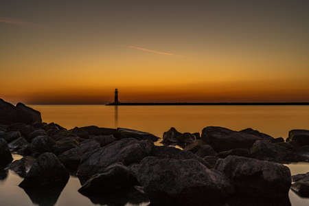 The entrance to a harbor with lighthouse at beautiful sunsetの写真素材