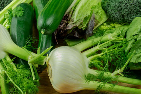 Delicacy green vegetables - fennel, zucchini, salad and broccoli. Useful vegetables on a wood boardの写真素材