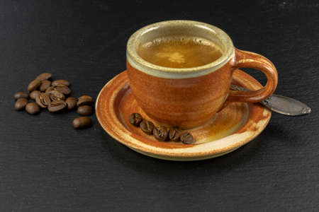 Coffee cup and saucer with coffee beans on a wooden table. Dark background of slateの写真素材