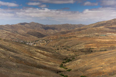A village in a barren mountain landscape with no trees and blue skyの写真素材