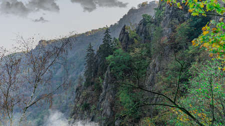 View in a valley with trees on the mountain and dark clouds in the skyの写真素材