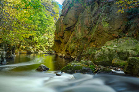 a small river in an autumn landscape with colorful leaves as a long time exposure