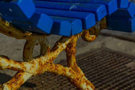 An old rusty park bench with blue wood as close up