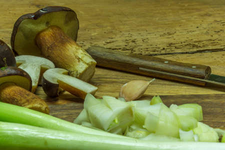 Vegetables and fresh mushrooms from the forest lie on a cutting board with a knifeの写真素材