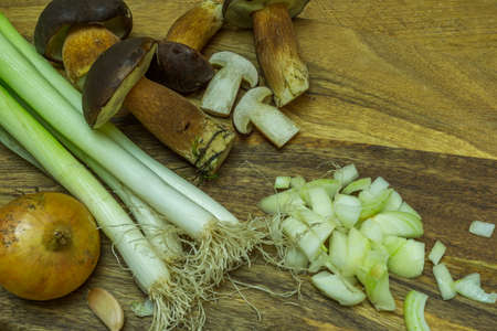 Vegetables and fresh mushrooms from the forest lie on a cutting board with a knifeの写真素材