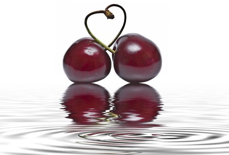 Cherries on a white background reflected on water.の写真素材