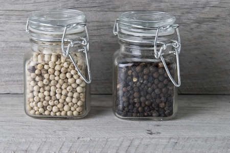 Black and white peppercorns on an old wooden surface.の写真素材