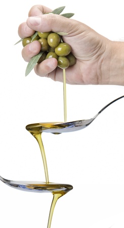 A hanful of olives dropping olive oil into a spoonの写真素材