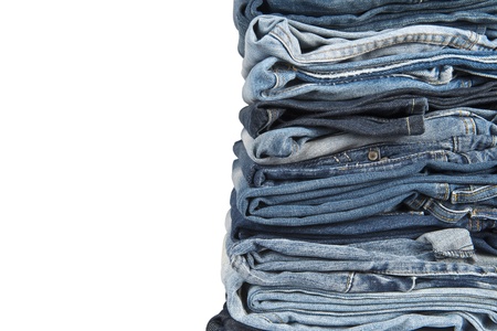Stack of old and worn blue jeans over a white backgroundの写真素材