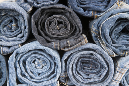Rolls of different worn and old blue jeans stackedの写真素材