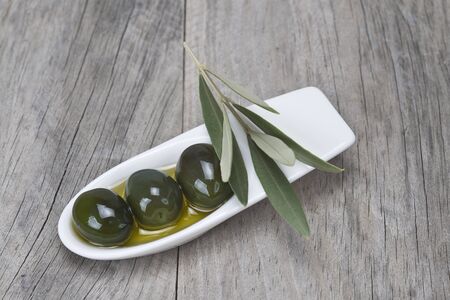A china spoon with olives and leaves on a wooden surface
の写真素材