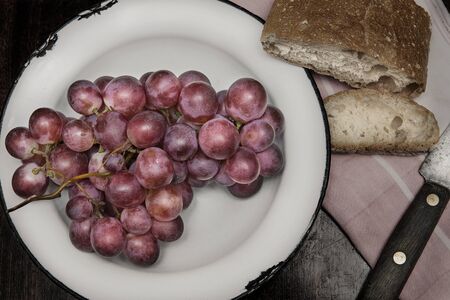 Still life with some bread and a bunch of grapes on a plate.の写真素材