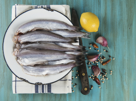 A plate with fish on the kitche table and ingredients to cook it の写真素材