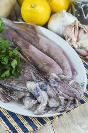 Fresh squids and some ingredients on the cutting board in the kitchenの写真素材