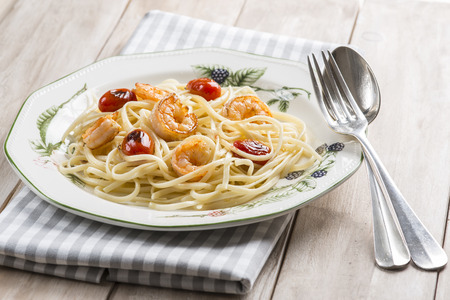 Spaghetti with prawns and grape tomatoes garnished with oregano and parsleyの写真素材